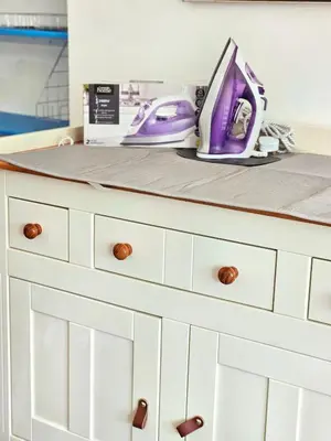 a white dresser with a purple iron on it at Parkside 2 bedrooms appartment with encolsed garden in Largs