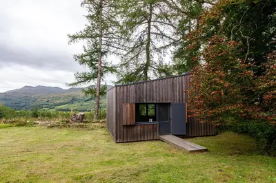 a small wooden house in the middle of a field at Railway Cottage in Killin