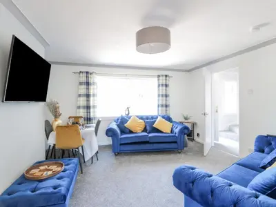 a living room with blue couches and a tv at 22 Turnberry Road in Girvan