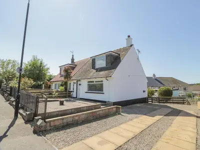 a white house with a fence in front of it at 22 Turnberry Road in Girvan