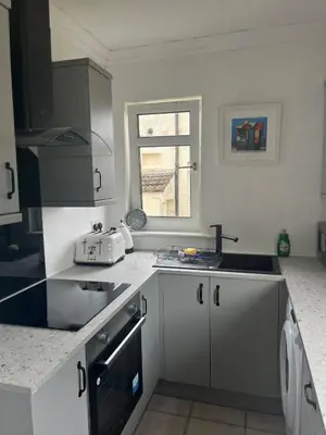 a kitchen with white cabinets and a sink and a window at Loch Lomond Apartment in Alexandria