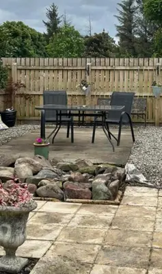 a patio with a table and chairs and a fence at Loch Lomond Apartment in Alexandria