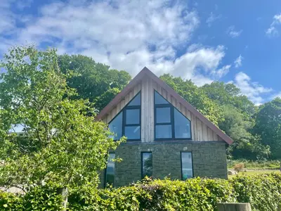 a house with a gambrel roof and trees at Còsagach Flat near Oban in Barcaldine