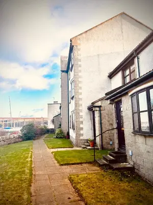 a white brick house with a sidewalk next to a yard at 3 Bedroom harbourside apartment, Queensferry, 10 miles from Edinburgh in Queensferry