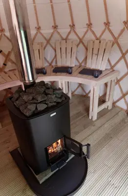 a wood fired stove in a room with two chairs at Eastside Steading - Family barn in the Pentland Hills, Edinburgh in Penicuik