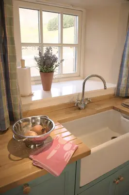 a kitchen with a sink and a bowl of fruit on a counter at Eastside Steading - Family barn in the Pentland Hills, Edinburgh in Penicuik