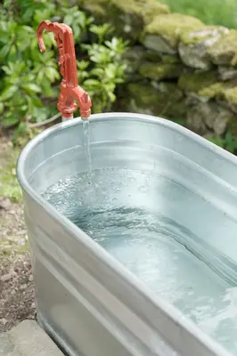 a faucet pouring water into a bucket of water at Eastside Byre - Family cottage in the Pentland Hills near Edinburgh in Penicuik