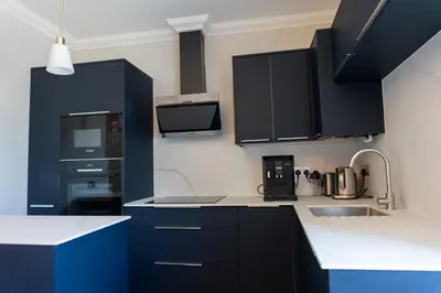 a kitchen with black cabinets and white counter tops at Oban Apartments in Oban