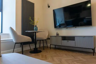 a living room with a table and two chairs and a tv at Oban Apartments in Oban