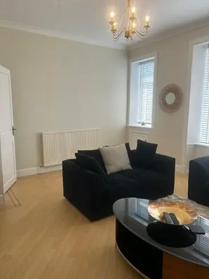 a living room with a black couch and a table at 1L Albert Place Maddiston Road Brightons Falkirk FK2 0JX in Polmont