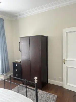 a bedroom with a wooden cabinet and a bed at 1L Albert Place Maddiston Road Brightons Falkirk FK2 0JX in Polmont