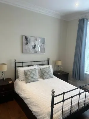 a bedroom with a large bed with two night stands at 1L Albert Place Maddiston Road Brightons Falkirk FK2 0JX in Polmont