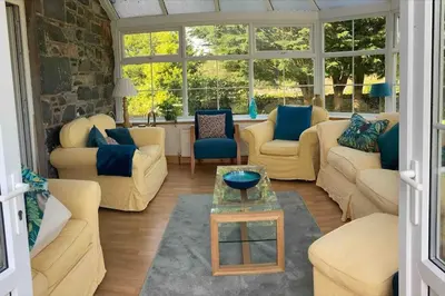 a living room with couches and a table and windows at Polharrow in Dalry