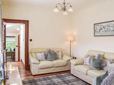 a living room with two couches and a chandelier at Sorbie Villa in Stevenston