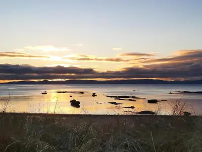a sunset over a body of water with rocks in it at Sorbie Villa in Stevenston
