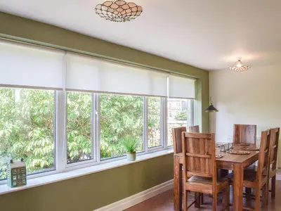 a dining room with windows and a table and chairs at Sorbie Villa in Stevenston