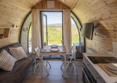 a tiny house with a table and chairs and a window at Macree Pod in Taynuilt