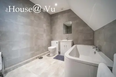 a bathroom with a white tub and a toilet at The Hoose at The Vu in Bathgate