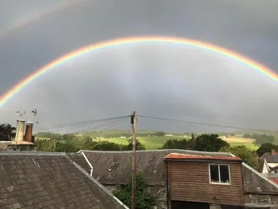 a rainbow in the sky over roofs of houses at Seamore House in Moffat