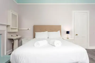 a white bedroom with a large white bed with two towels at Burnock Lodge with Hot Tub in Ayr