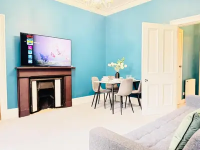 a living room with a table and a tv on a wall at City Centre Escape with Private Garden in Edinburgh