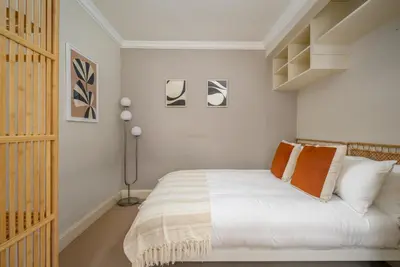 a bedroom with a bed with white sheets and orange pillows at New Town Garden Retreat by Calton Living in Edinburgh