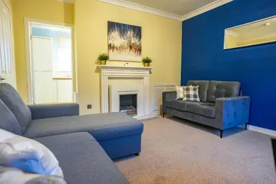 a living room with two couches and a fireplace at West Apartment in Coatbridge