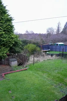 a backyard with a fence and a yard with green grass at West Apartment in Coatbridge