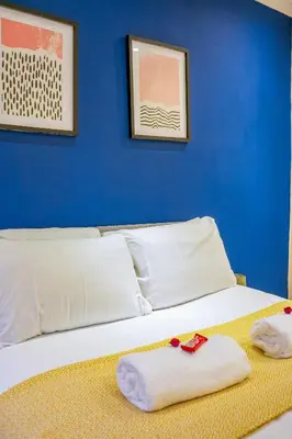 a bed with white pillows and a blue wall at West Apartment in Coatbridge