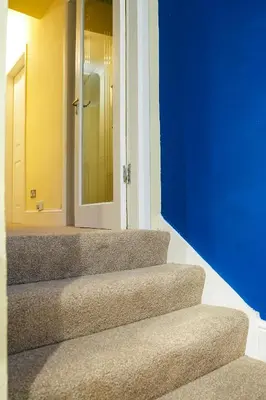 a set of stairs with a blue wall and a door at West Apartment in Coatbridge