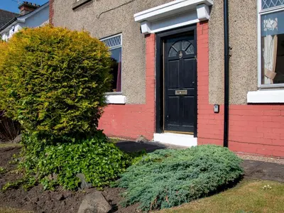 a bush in front of a house with a black door at Private Entrance GF 2 bed flat near Renfrew Centre - Pass the Keys in Renfrew
