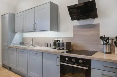 a kitchen with white cabinets and a sink and a stove at The Woodside Apartments in Doune