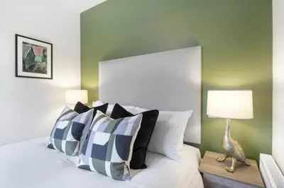 a bed with black and white pillows and a lamp at The Woodside Apartments in Doune