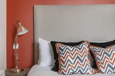 a bed with black and white pillows and a lamp at The Woodside Apartments in Doune