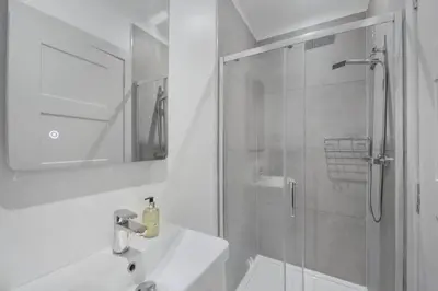 a white bathroom with a shower and a sink at The Woodside Apartments in Doune
