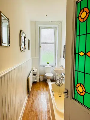 a bathroom with a toilet and a sink and a window at THE LAZY LION - Spacious 2 Bedroom - Town Centre Holiday Home Apartment in Port Glasgow