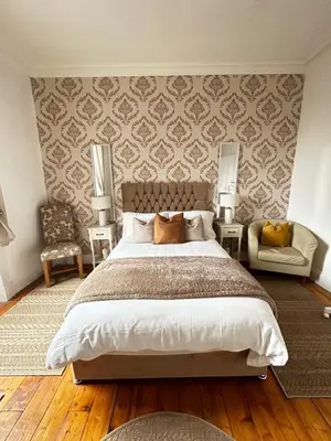 a bedroom with a large bed and two chairs at THE LAZY LION - Spacious 2 Bedroom - Town Centre Holiday Home Apartment in Port Glasgow