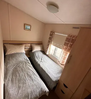 two beds in a small room with a window at 4-Bedroom Cosalt Located in Uddingston, Glasgow at Maryville Caravan Site in Uddingston
