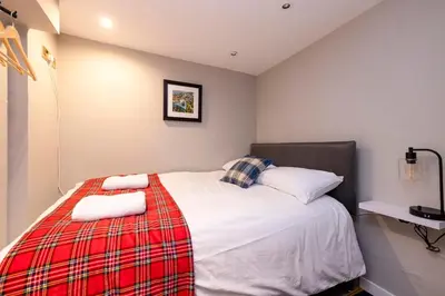 a bedroom with a bed with a red plaid blanket at New Town Rooms in Edinburgh