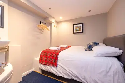 a small bedroom with a bed and a sink at New Town Rooms in Edinburgh