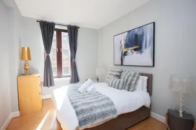 a bedroom with a bed with a blanket and a window at Modern and refurbished Flat in Merchant City in Glasgow