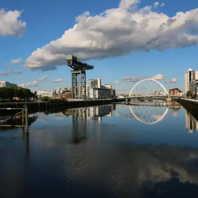 a bridge over a river with a city in the background at Modern and refurbished Flat in Merchant City in Glasgow