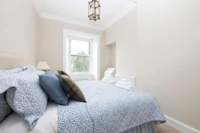 a bedroom with a bed with a blue comforter and a window at Deluxe 3-bedroom Apartment on Princes Street overlooking Edinburgh Castle in Edinburgh