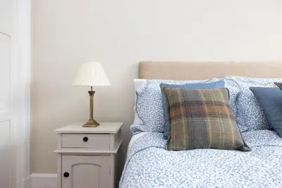 a bedroom with a bed with a lamp on a night stand at Deluxe 3-bedroom Apartment on Princes Street overlooking Edinburgh Castle in Edinburgh