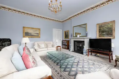 a living room with a white couch and a tv at Deluxe 3-bedroom Apartment on Princes Street overlooking Edinburgh Castle in Edinburgh