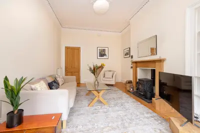 a living room with a white couch and a fireplace at Tasteful 1-bedroom Apartment near Edinburgh Meadows in Edinburgh
