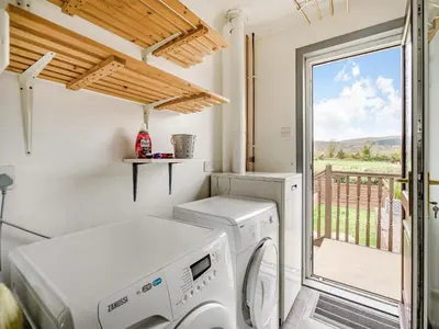 a laundry room with a washing machine and a window at Highview in Brodick