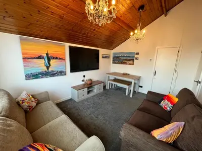 a living room with two couches and a flat screen tv at The Mail Barn Studio in Lamlash