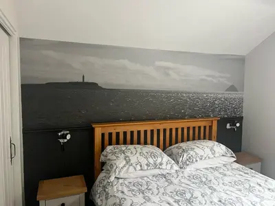 a bedroom with a bed with a view of the ocean at The Mail Barn Studio in Lamlash