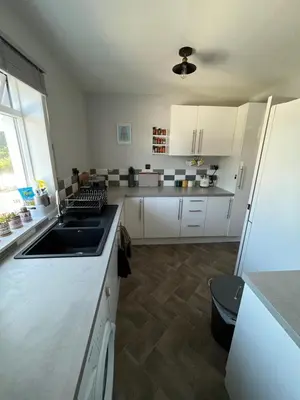 a kitchen with white cabinets and a sink at The Mail Barn Studio in Lamlash